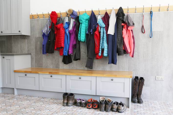 row of coats on hung on coat rail with boots lined up on floor