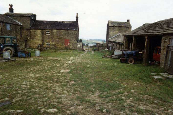 View of farm yard with tractors and buildings in background
