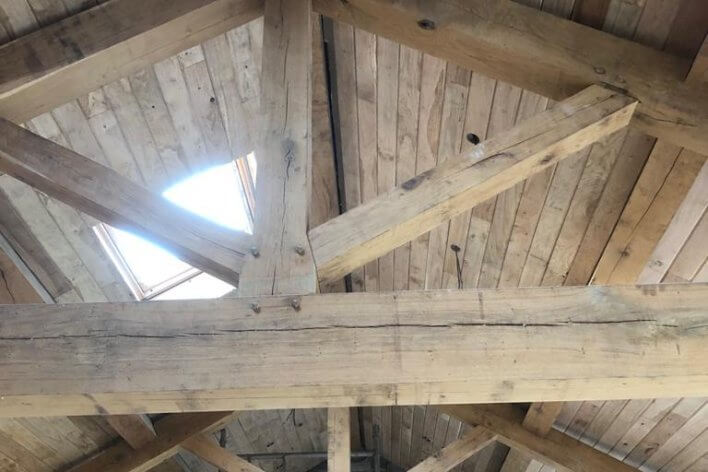Looking up to wooden beams and wood-clad roof with roof window