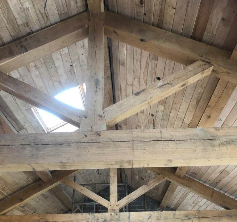 Looking up to wooden beams and wood-clad roof with roof window