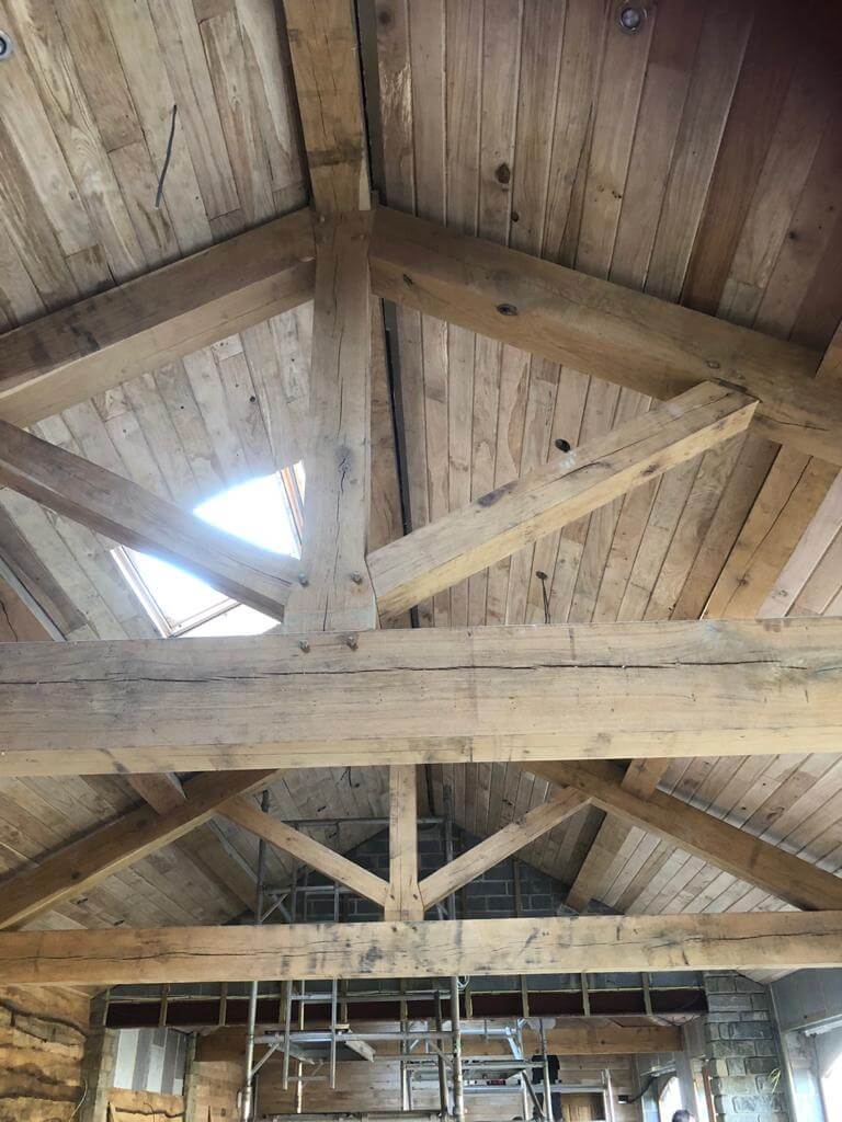 Looking up to wooden beams and wood-clad roof with roof window