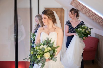Bride and two bridesmaids looking through window