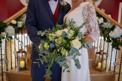 Close up of couple in wedding attire with bouquet of flowers in foreground