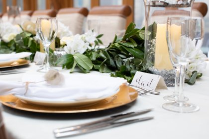 Close up of dining place setting with candles and foliage centrepiece