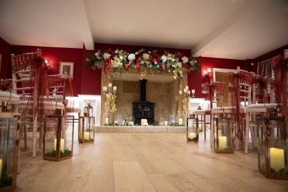 Room arranged for ceremony with chairs, candles in glass lanterns and flower garland above fireplace