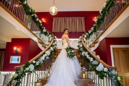Bride on stairs with garlands of flowers and glass candle lanterns