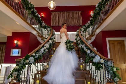 Bride on stairs with garlands of flowers and glass candle lanterns