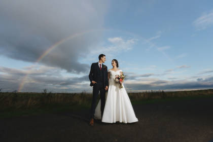 bridal couple outdoors with rainbow